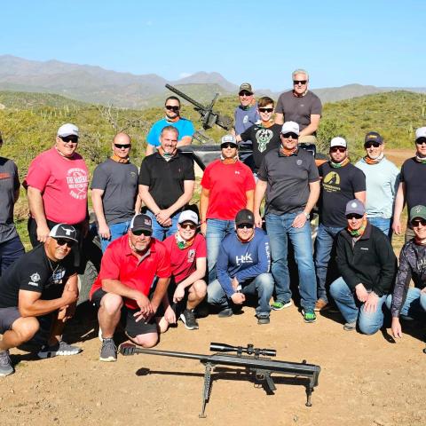 Group of people posing outside with a scenic mountain backdrop.