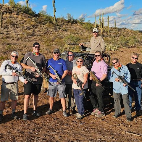 A group of people holding guns in a desert landscape with cacti.