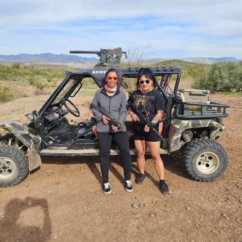 Two people standing in front of an ATV on a desert trail.