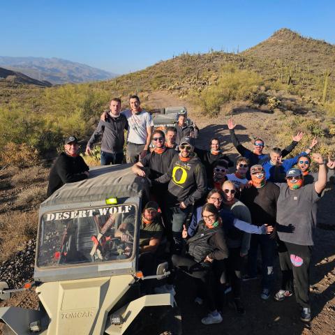 Group of people posing with off-road vehicles in a desert landscape.